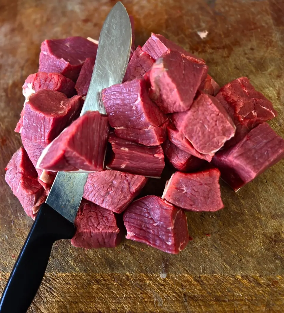 Diced red meat and a knife on the shop's wooden chopping board